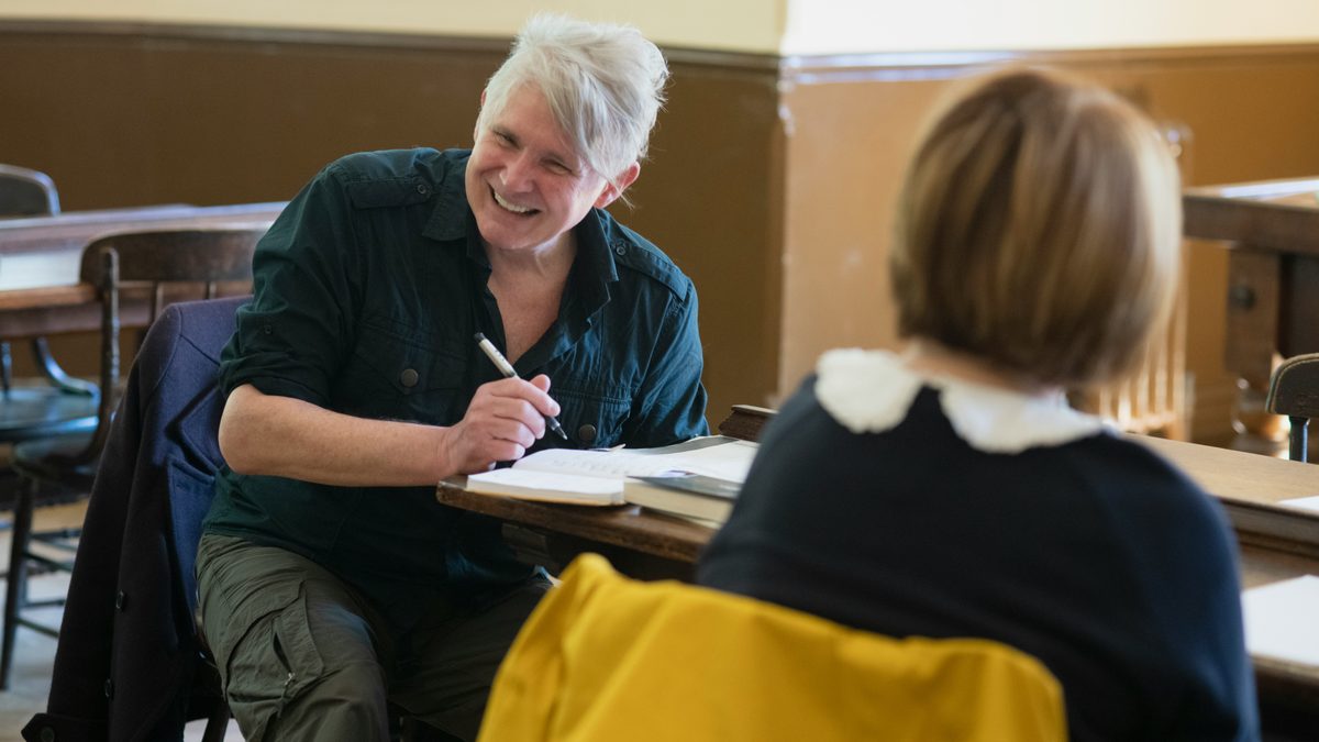 Person writing in a notebook at a table.