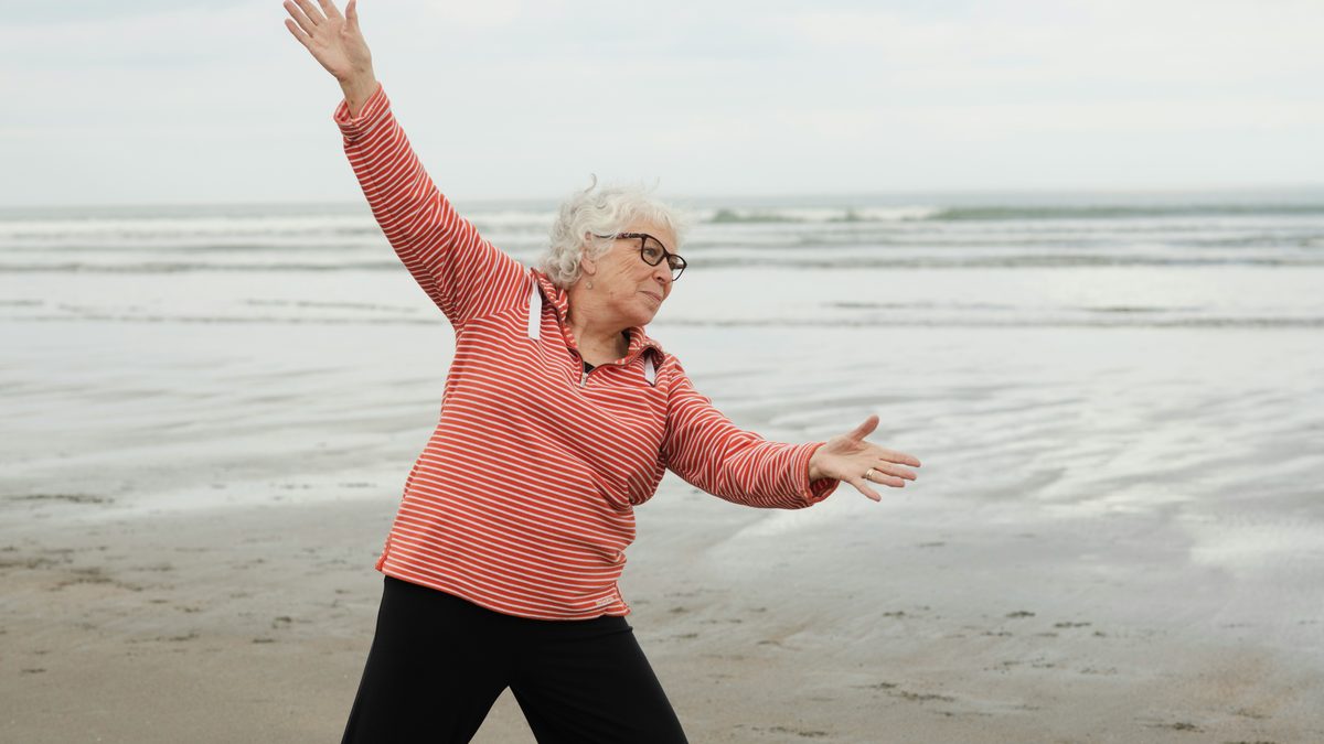 Older adult stretching at the beach.