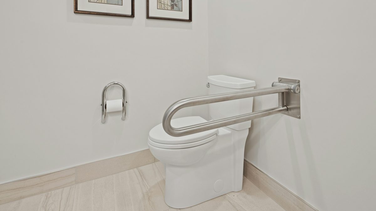 Bathroom toilet with an accessibility grab bar.